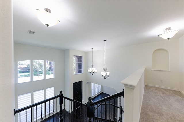 staircase with a chandelier and carpet flooring