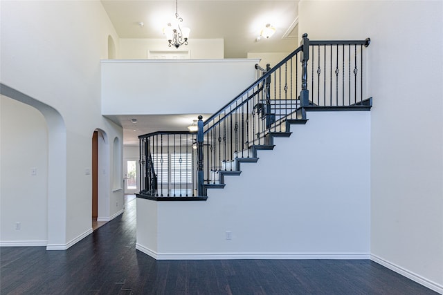 stairs with a high ceiling, hardwood / wood-style flooring, and a chandelier