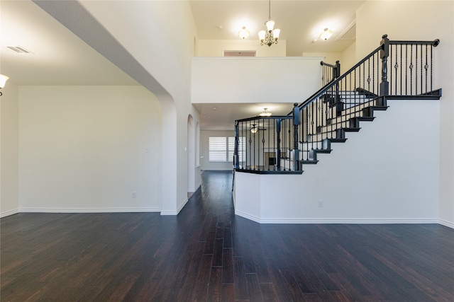 entryway featuring a towering ceiling, dark hardwood / wood-style flooring, and a chandelier