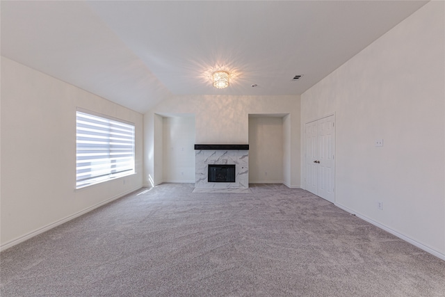 unfurnished living room featuring light colored carpet, lofted ceiling, and a high end fireplace