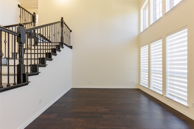 stairs with a towering ceiling, wood-type flooring, and plenty of natural light