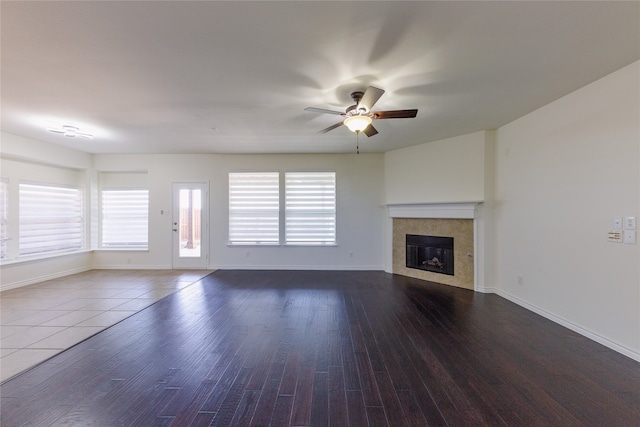 unfurnished living room featuring a fireplace, dark hardwood / wood-style floors, and ceiling fan