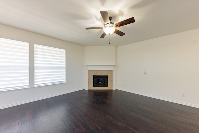 unfurnished living room featuring a tiled fireplace, dark wood-type flooring, and ceiling fan