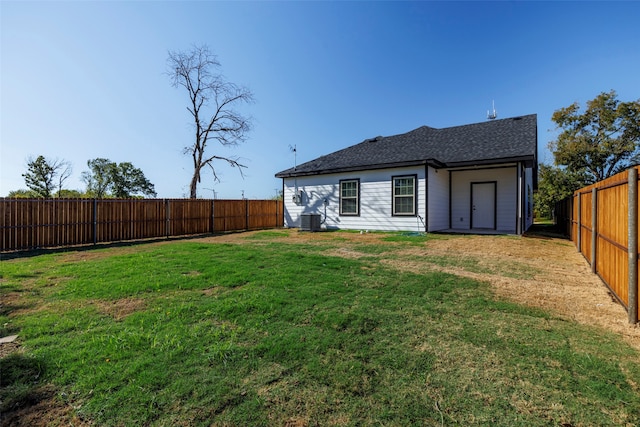 rear view of property with central AC and a yard