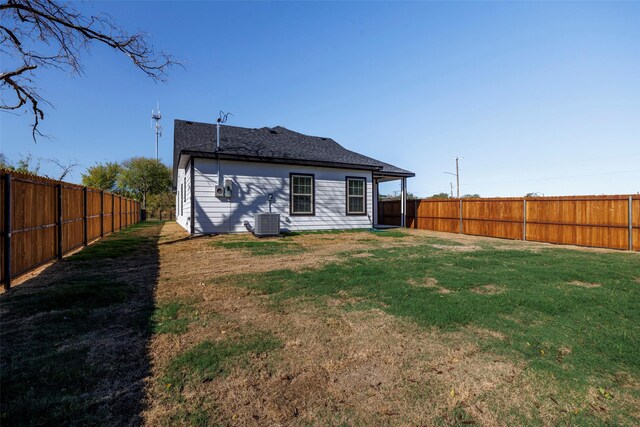 rear view of property with a lawn and cooling unit