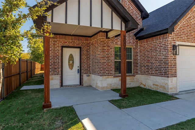 entrance to property with a garage and a lawn