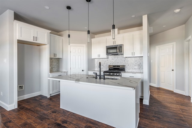 kitchen featuring dark hardwood / wood-style flooring, a kitchen island with sink, light stone countertops, white cabinetry, and appliances with stainless steel finishes