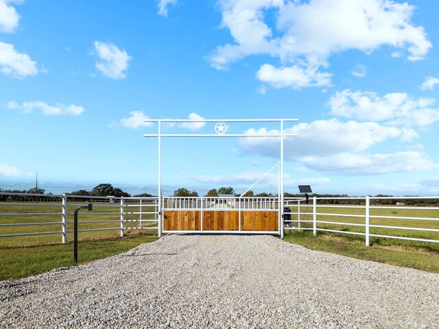 view of gate with a rural view and a yard