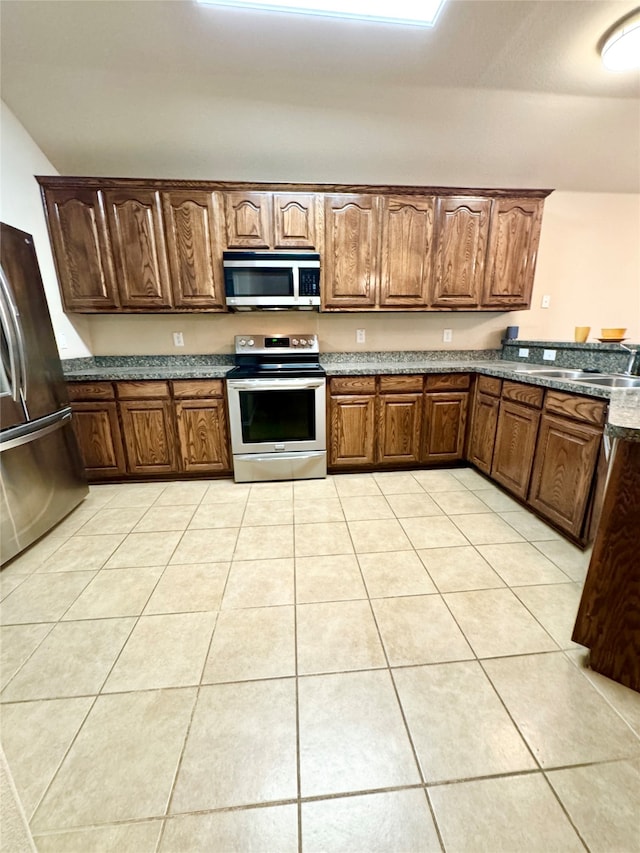 kitchen with stainless steel appliances, sink, and light tile patterned floors