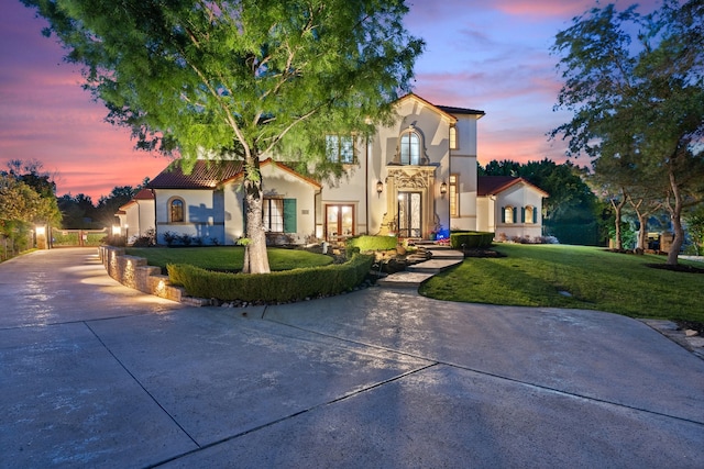 mediterranean / spanish house with a lawn and french doors