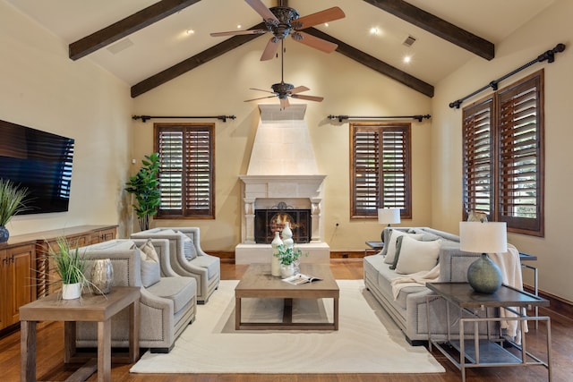 living room featuring beamed ceiling, wood-type flooring, high vaulted ceiling, and a tiled fireplace