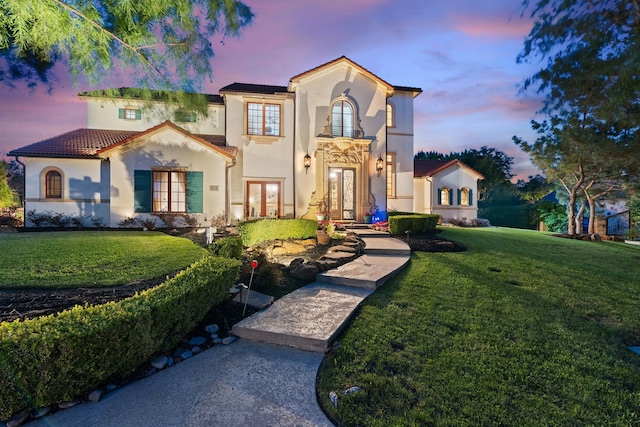 mediterranean / spanish house featuring a yard and french doors