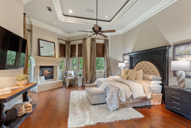 bedroom featuring a raised ceiling, ceiling fan, dark hardwood / wood-style flooring, and crown molding