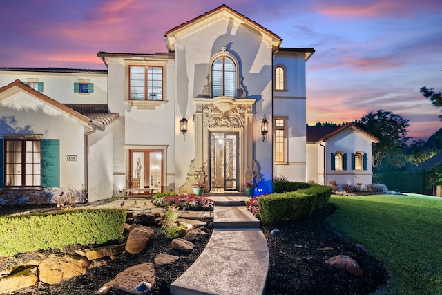 mediterranean / spanish-style home featuring a yard and french doors