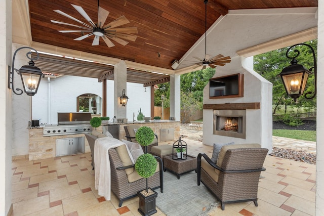 view of patio featuring ceiling fan, an outdoor kitchen, exterior fireplace, and grilling area