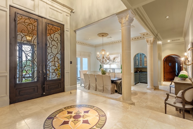 entrance foyer featuring french doors, decorative columns, an inviting chandelier, and ornamental molding