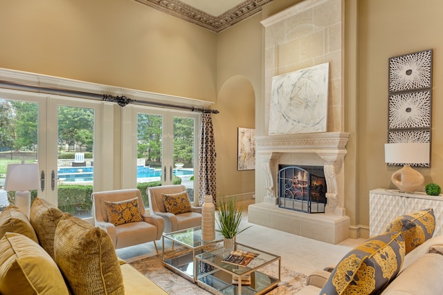 living room featuring a tiled fireplace, a high ceiling, a wealth of natural light, and french doors