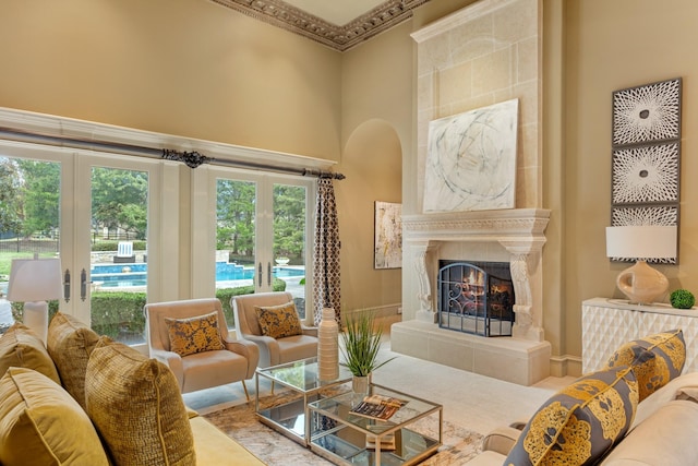 living room with ornamental molding, a towering ceiling, and a high end fireplace