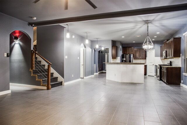 kitchen featuring stainless steel appliances, light stone countertops, hanging light fixtures, and an island with sink