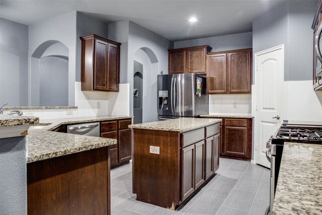 kitchen with a center island, kitchen peninsula, dark brown cabinetry, sink, and appliances with stainless steel finishes