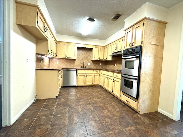 kitchen featuring a textured ceiling, tasteful backsplash, light brown cabinets, appliances with stainless steel finishes, and sink