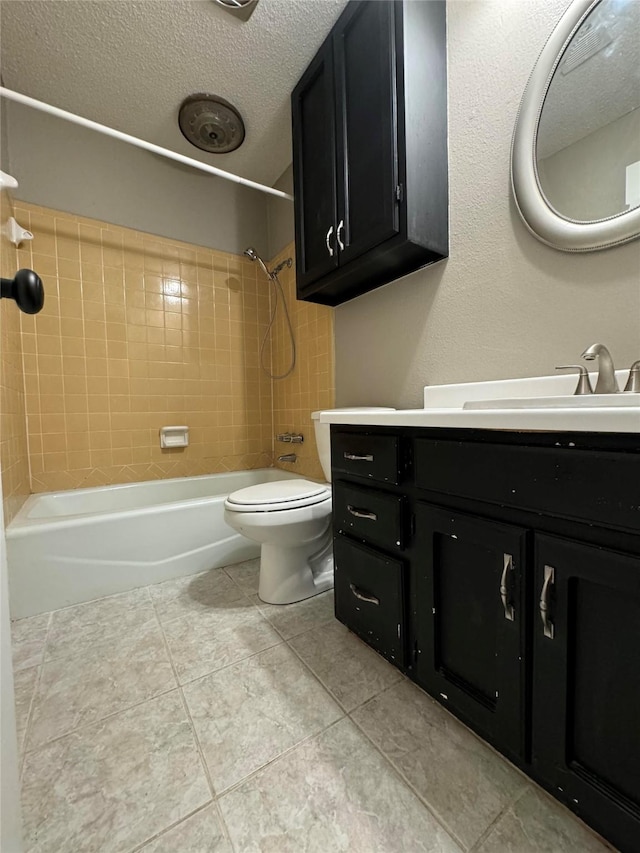 full bathroom featuring a textured ceiling, tiled shower / bath combo, vanity, and toilet