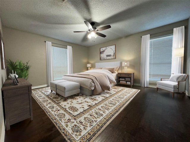 bedroom featuring dark wood-type flooring, a textured ceiling, and ceiling fan