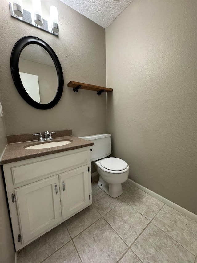 bathroom with toilet, a textured ceiling, tile patterned floors, and vanity