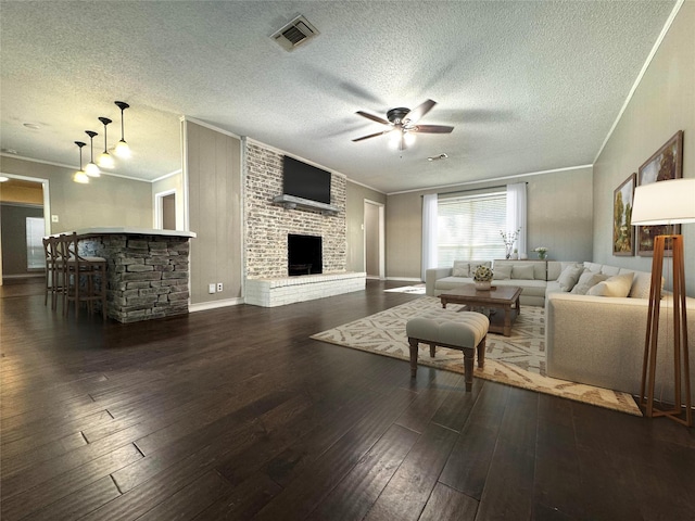 living room with a brick fireplace, ceiling fan, crown molding, and dark hardwood / wood-style floors