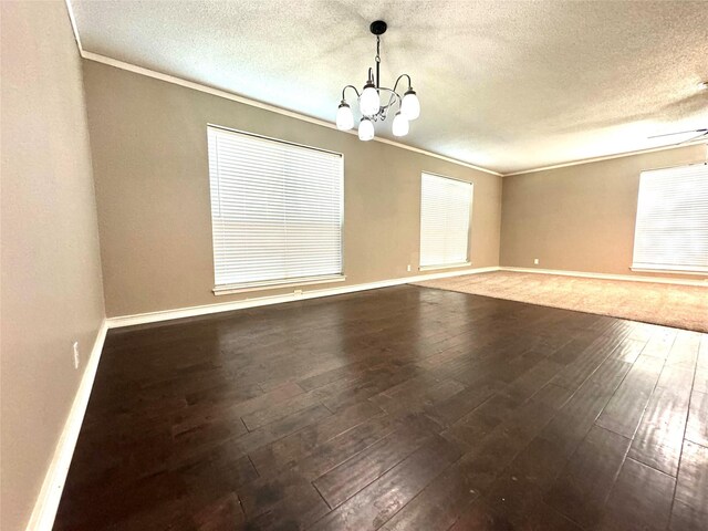 unfurnished room with a textured ceiling, a chandelier, ornamental molding, and dark hardwood / wood-style floors