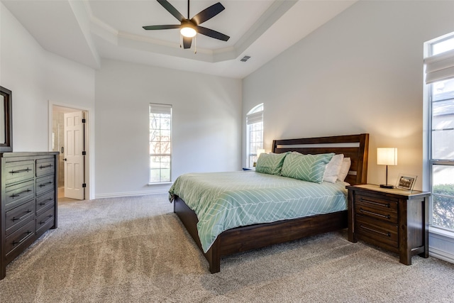 bedroom with a tray ceiling, ceiling fan, crown molding, and light colored carpet