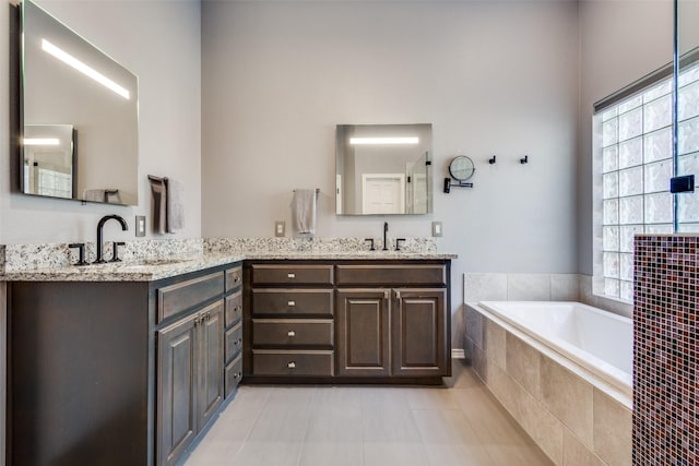 bathroom featuring tile patterned flooring, vanity, tiled tub, and a wealth of natural light