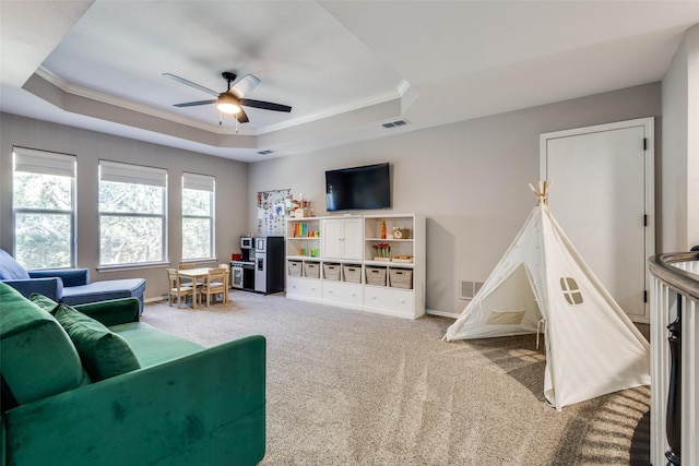 carpeted living room with ceiling fan, ornamental molding, and a tray ceiling