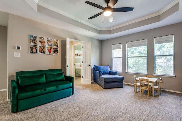 living area with a raised ceiling, ceiling fan, crown molding, and carpet floors