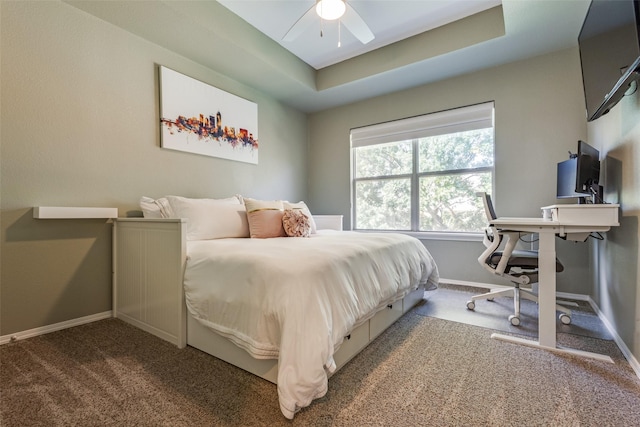 carpeted bedroom featuring a tray ceiling and ceiling fan