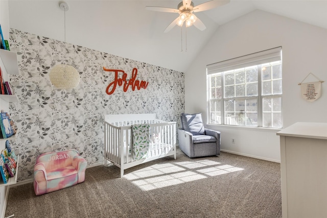 unfurnished bedroom with carpet flooring, ceiling fan, a crib, and vaulted ceiling