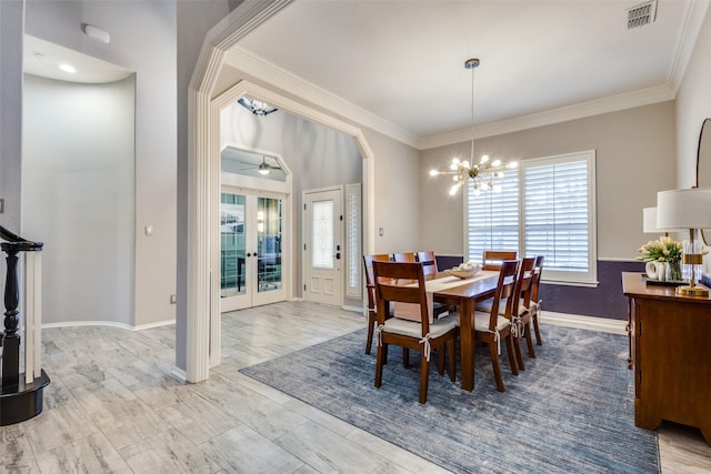 dining space with crown molding, french doors, and ceiling fan with notable chandelier