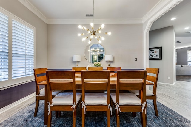 dining area featuring wood-type flooring, ornamental molding, and a notable chandelier