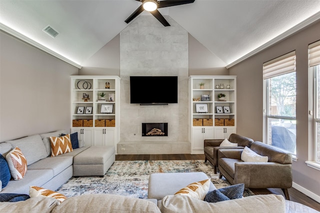 living room featuring ceiling fan, a large fireplace, wood-type flooring, and lofted ceiling