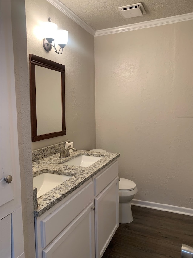 bathroom featuring toilet, hardwood / wood-style floors, a textured ceiling, vanity, and crown molding