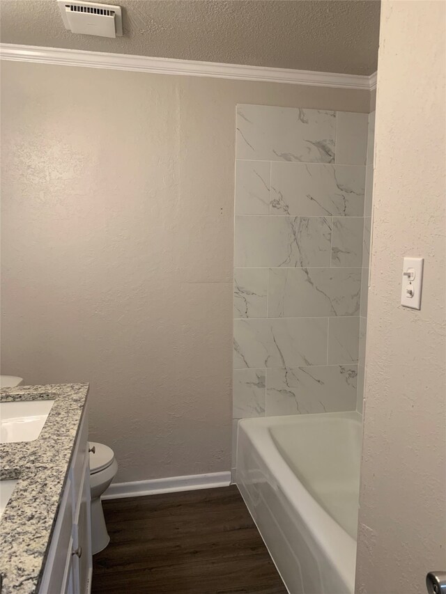 full bathroom with ornamental molding, vanity, a textured ceiling, hardwood / wood-style flooring, and toilet