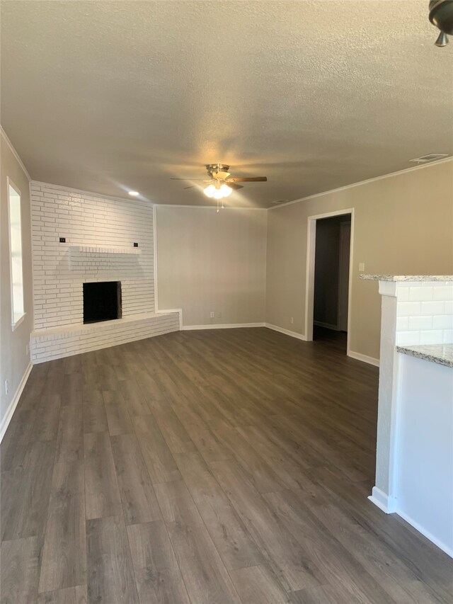 unfurnished living room featuring a brick fireplace, ceiling fan, a textured ceiling, and dark hardwood / wood-style flooring