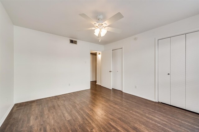 unfurnished bedroom featuring dark wood-type flooring, two closets, and ceiling fan