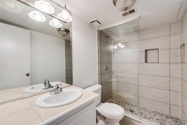 bathroom featuring a tile shower, vanity, and toilet