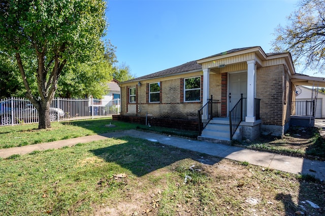 view of front of property featuring a carport, brick siding, a front lawn, and fence