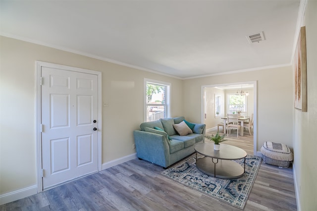 living room with hardwood / wood-style flooring, an inviting chandelier, and crown molding