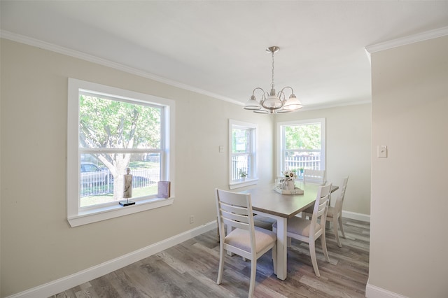 dining area with hardwood / wood-style floors, a wealth of natural light, crown molding, and a notable chandelier