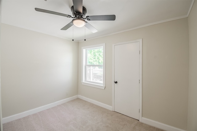 spare room with ceiling fan, light colored carpet, and ornamental molding