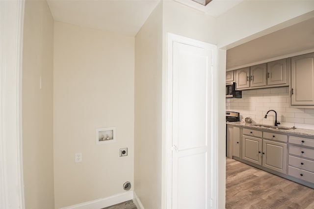 clothes washing area with hookup for a washing machine, sink, light hardwood / wood-style floors, and hookup for an electric dryer