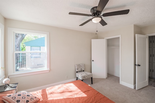 bedroom with ceiling fan, a closet, light colored carpet, and a textured ceiling